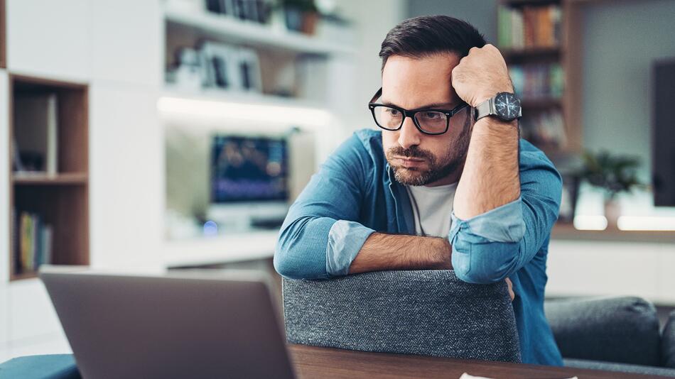 Mann sitzt verzweifelt vor dem Laptop