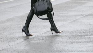 Frau mit High Heels geht über eine regennasse Straße