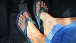 Frau mit Flip-Flops am Steuer eines Autos