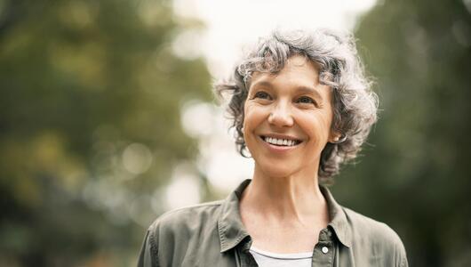 Lächelnde Frau mit grauen Locken (Symbolbild). 