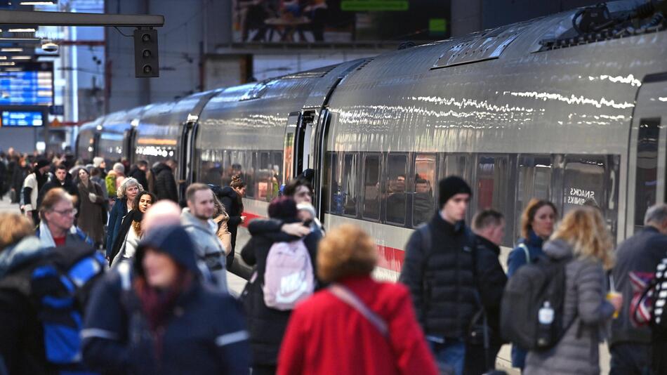 Viele Personen laufen am Bahnsteig vor einem ICE.