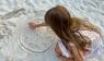 Kind malt eine Uhr in den Sand