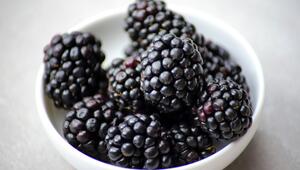 Schwarze Brombeeren in einer weißen Schale vor hellem Hintergrund.