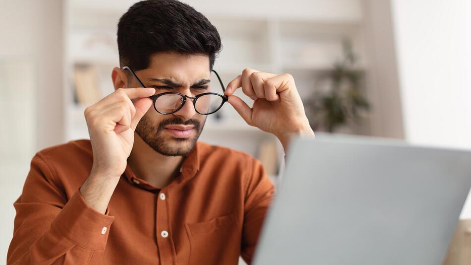 Mann mit Brille vor einem Laptop