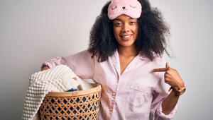 Frau im Schlafanzug und Wäschekorb im Arm