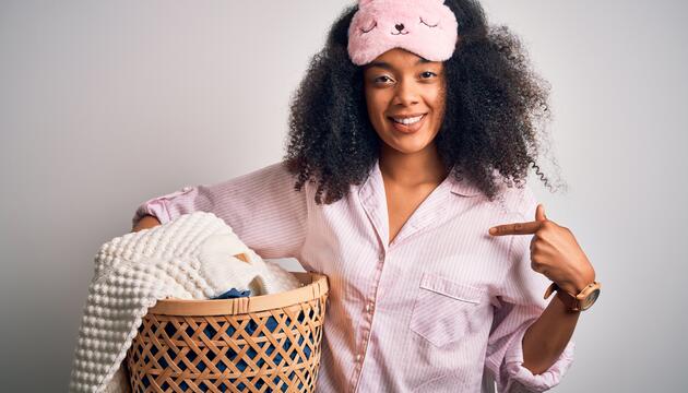 Frau im Schlafanzug und Wäschekorb im Arm