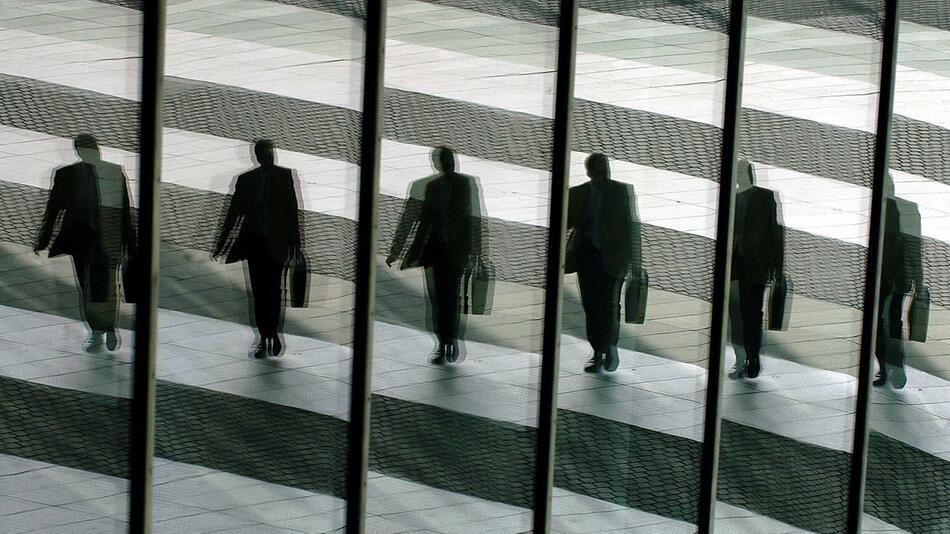 Mann spiegelt sich in den Glasscheiben eines Büros