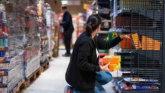 Mitarbeiterin eines Supermarktes beim Sortieren von Produkten