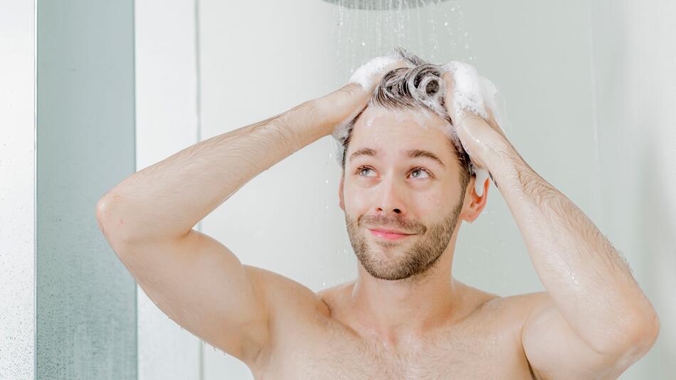 Mann wäscht sich unter der Dusche die Haare