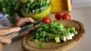 Eine Frau schneidet beim Kochen Lauchzwiebeln