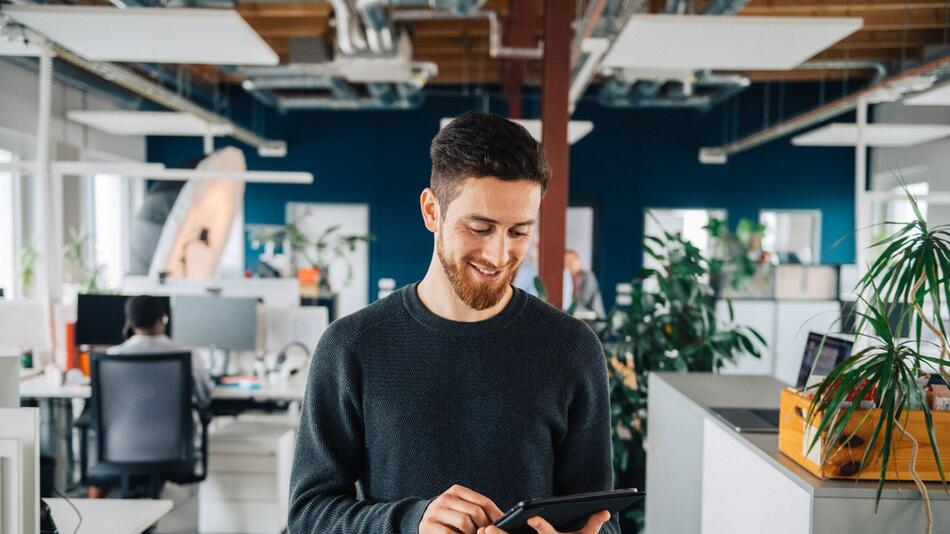 Mann mit Tablet in einem Großraumbüro