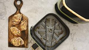 Schweinekotellet mit Zwiebeln liegt auf einem Holzbrett. Danben der Airfryer.