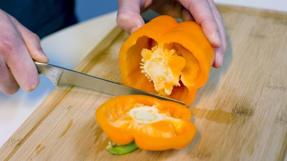 Mann schneidet eine Paprika auf