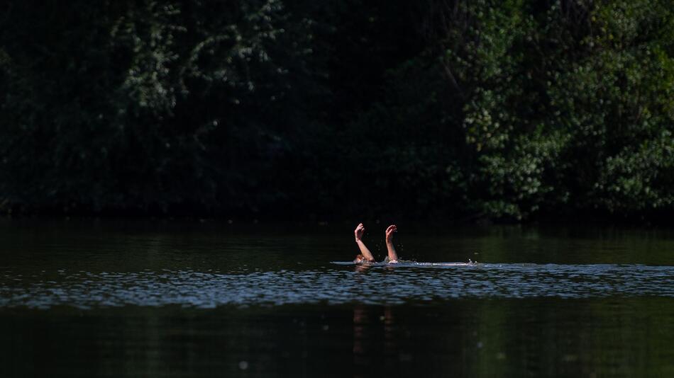 Eine Schwimmerin streckt die Hände aus dem Wasser