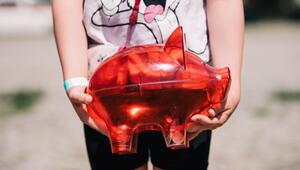 Ein Kind trägt ein rotes Sparschwein
