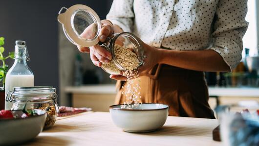 Frau mit Haferflocken in Küche.