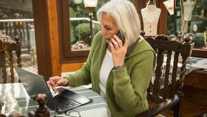 Seniorin mit Smartphone und Laptop