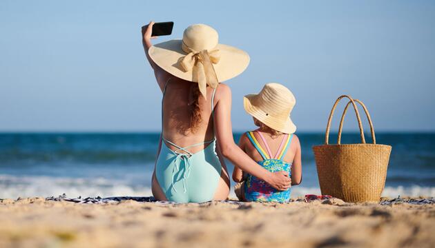 Mutter und Tochter machen ein Selfie am Strand