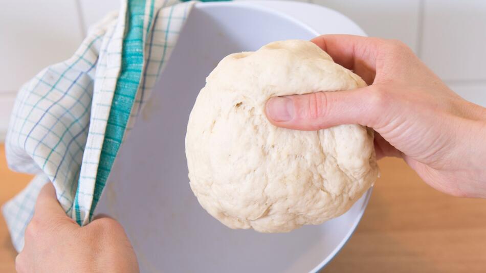 Frau hält einen Hefeteig in der Hand