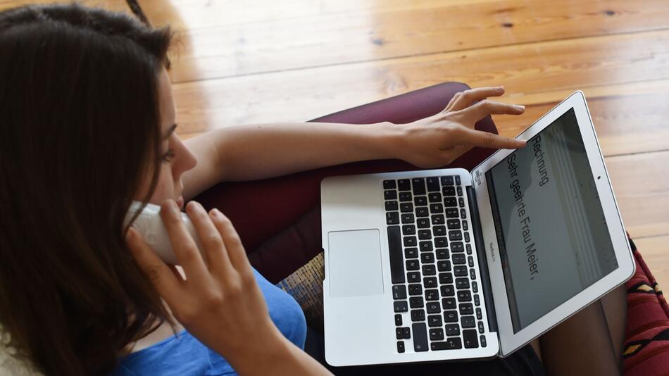 Frau mit Laptop telefoniert