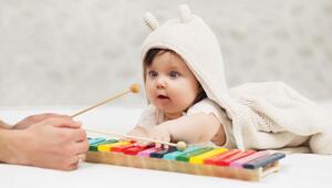 Baby, das am Glockenspiel sitzt und Mutter zusieht. 