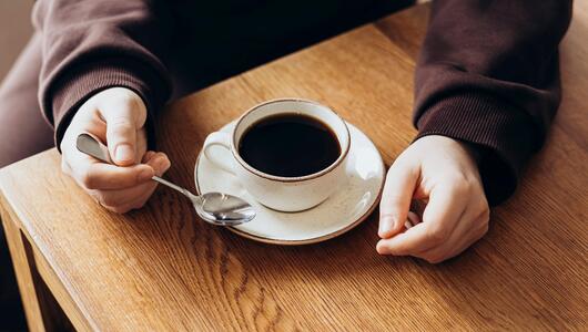Hände und eine Tasse Kaffee auf einem Tisch