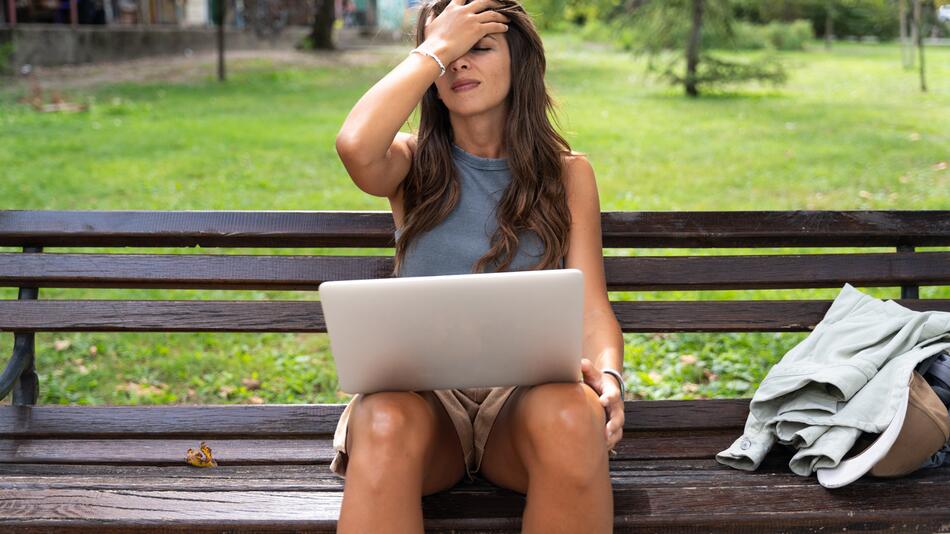 Eine Frau mit einem Laptop auf dem Schoss.