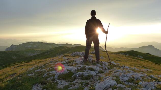 Wanderer genießt bei Sonnenuntergang die Aussicht über die Berge