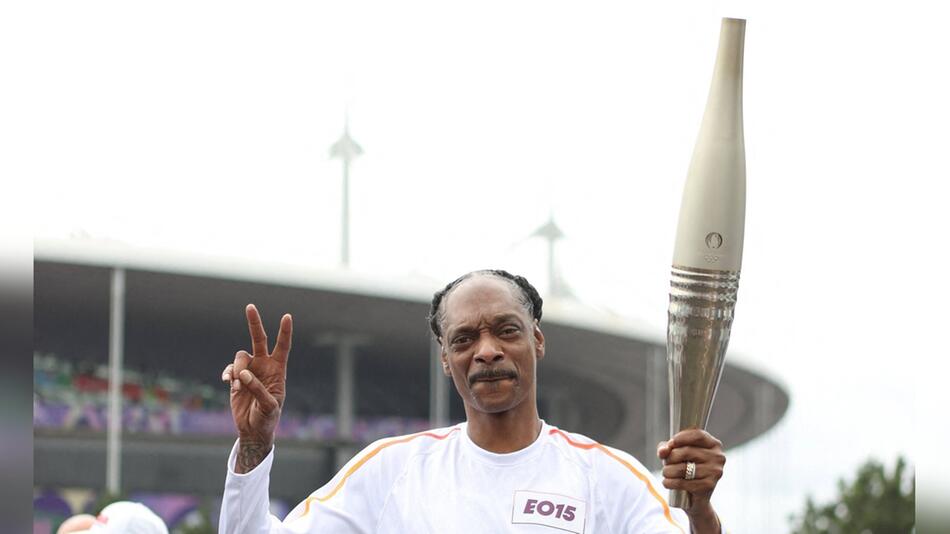 Snoop Dogg trägt die olympische Fackel in Paris.