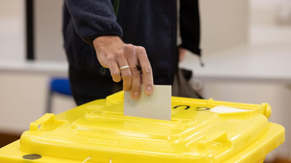 Wähler wirft Stimmzettel in eine Wahlurne