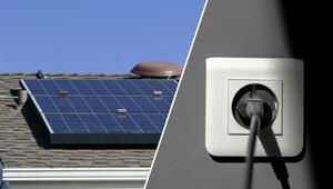 Solarmodule auf einem Hausdach bei klarem Himmel und eine weiße Steckdose mit eingestecktem ...