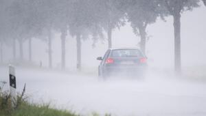 Ein Auto fährt bei Starkregen über eine Landstraße