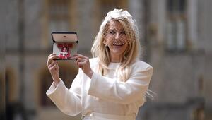 Ellie Goulding zeigt stolz ihren MBE-Orden.