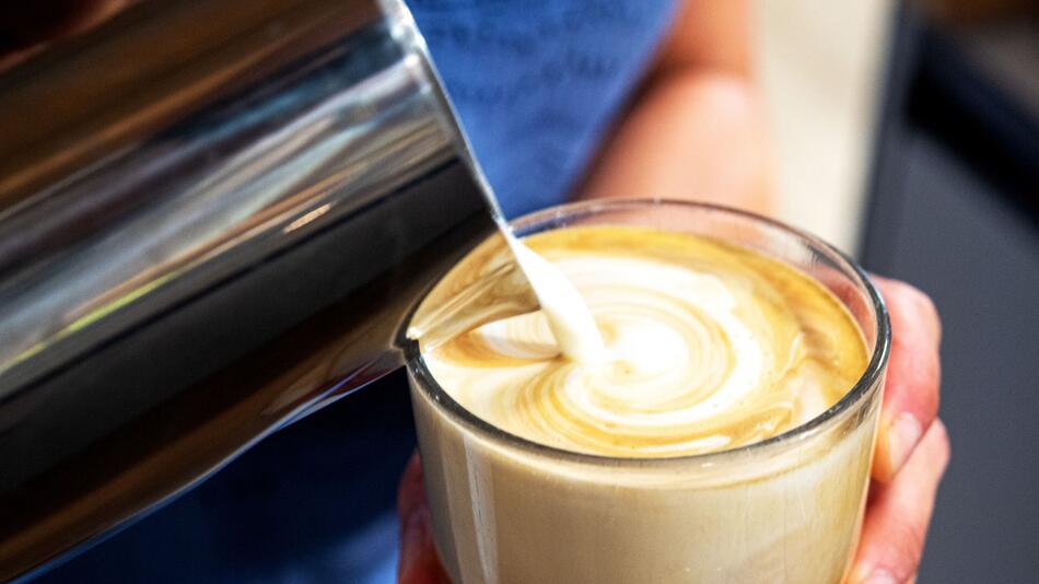 Milch wird in einen Kaffee gegossen