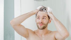 Ein junger Mann wäscht sich die Haare unter der Dusche