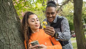 Ein junger Mann überrascht seine Freundin im Park mit Blümchen