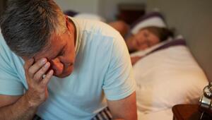 Mann, der an Bettkante sitzt und ernst schaut. 