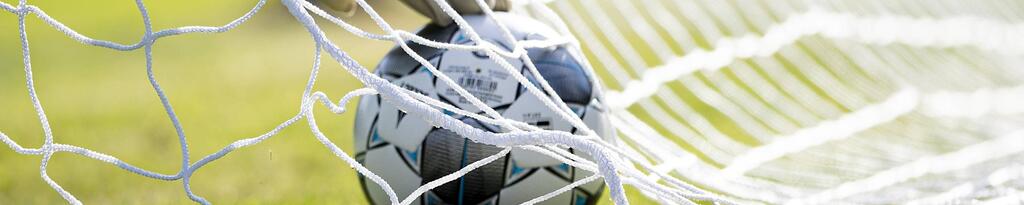 Ein Torwart muss den Ball aus dem Tornetz holen