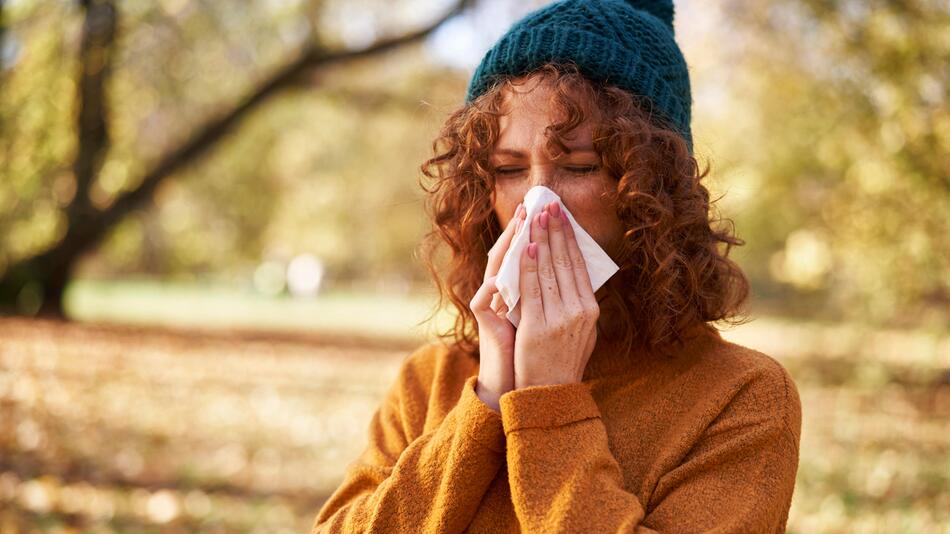 Eine Frau mit Allergieproblemen schnäuzt sich die Nase