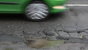 Ein Pkw fährt auf einer Straße voller Schlaglöcher