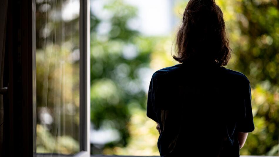 Eine Frau steht an einem offenen Fenster