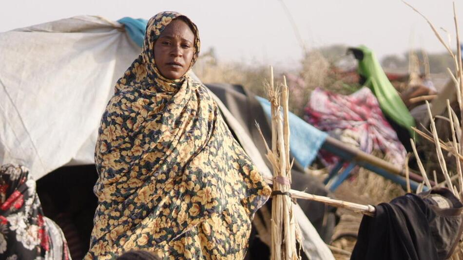 Eine Frau in einem Geflüchtetencamp mit einem Wasserkanister.