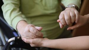 Eine junge Frau hält die Hände eines alten Mannes