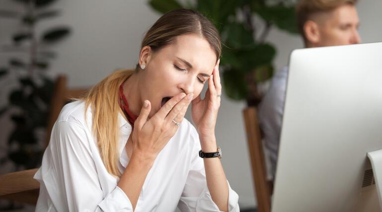 Junge Frau am Computer, die gähnen muss