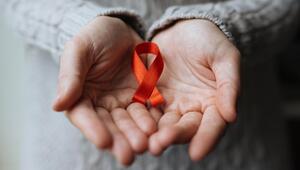 Hände halten die für den Welt-Aids-Tag charakteristische rote Schleife