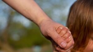 Ein junger Vater hält die Hand seines kleinen Kindes