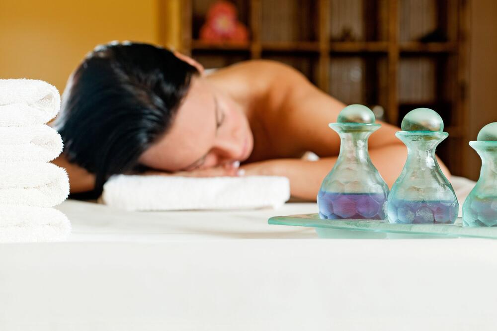 Frau liegt in Wellnesshotel auf einer Massageliege