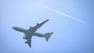 Ein Flugzeug fliegt unterhalb eines Kondensstreifens