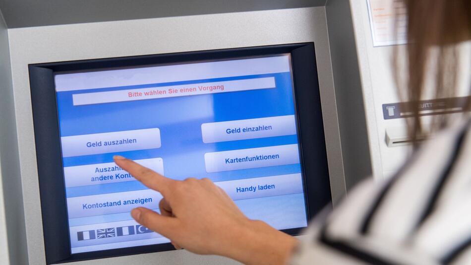 Frau hebt Geld an einem Automaten ab