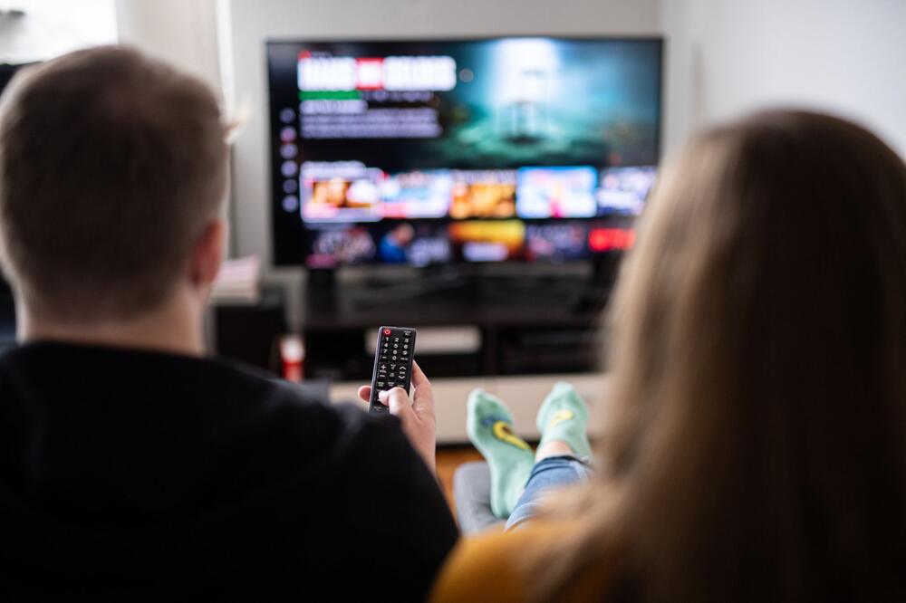Paar sitzt vor einem Fernseher mit Streamingdiensten